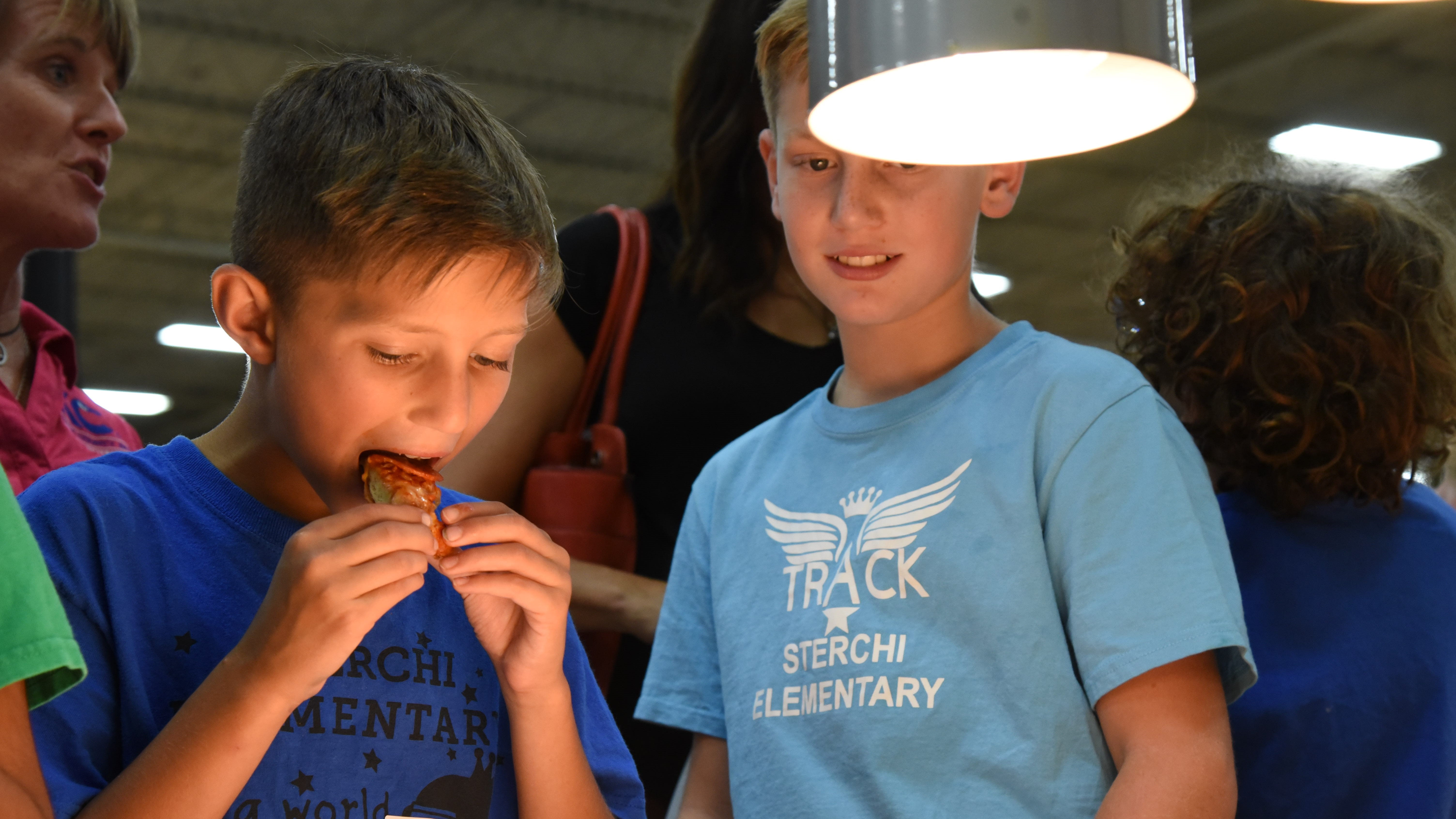 Neko Yoder, a 4th-grader at Sterchi Elementary, tries a sample at the KCS Food Show on Sept. 12, 2019, as Jake Owen looks on. 